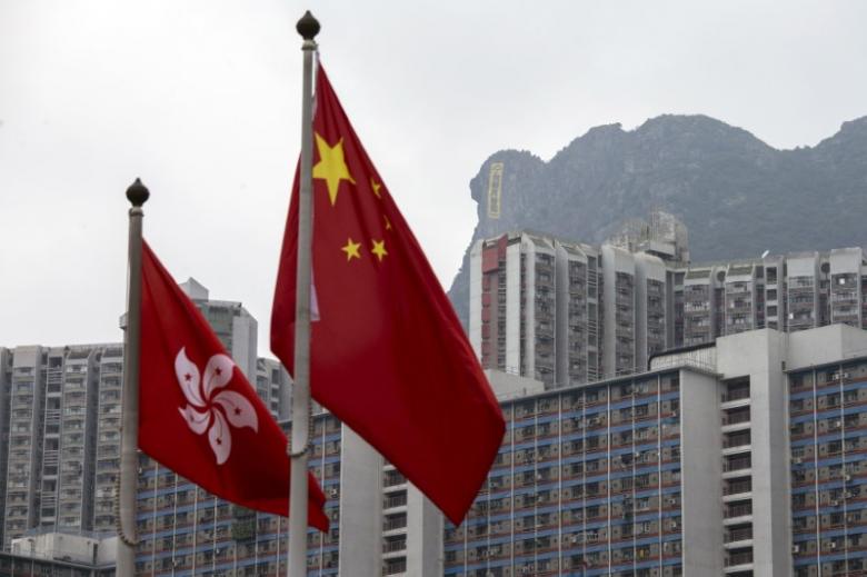 The flags of Hong Kong and China are seen in front of a large banner that was hung by pro-democracy protesters at Lion Rock on October 23, 2014. Photo: Tyrone Siu/Reuters