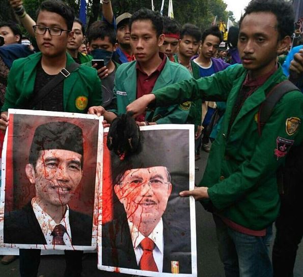 Student protesters holding up posters of President Joko Widodo and Vice President Jusuf Kalla covered in the blood of a freshly beheaded chicken on October 20. Photo: @doniherdaru / Instagram