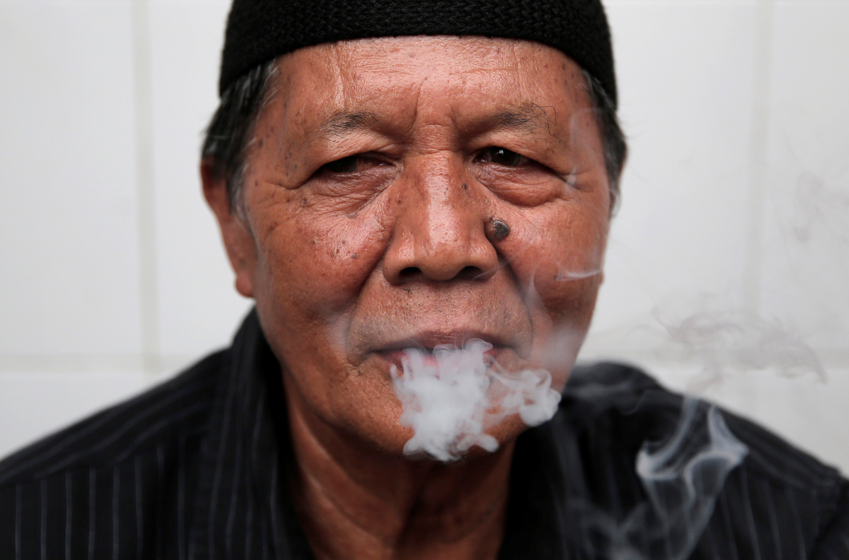 A man smokes s cigarette in Jakarta, Indonesia, March 14, 2017. Picture taken March 14, 2017. REUTERS/Beawiharta