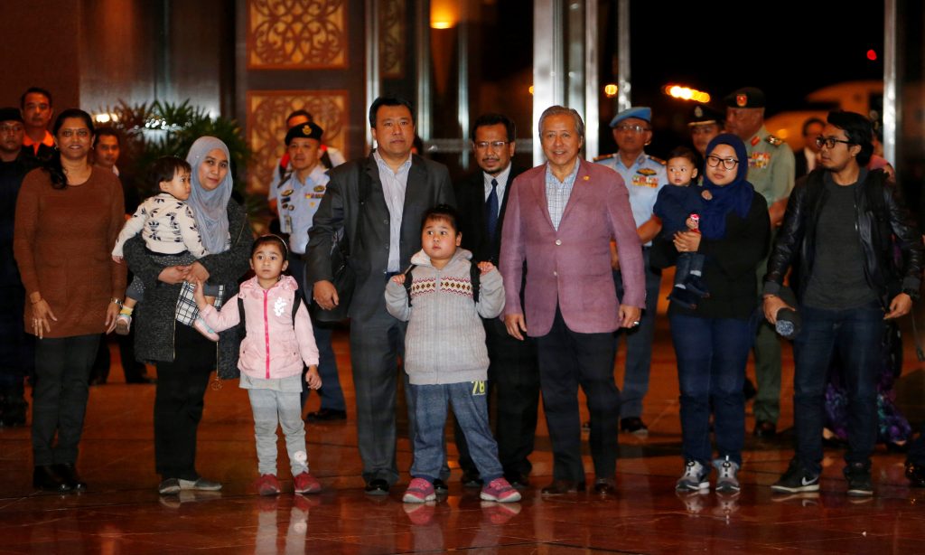 Malaysia's Foreign Minister Anifah Anan walks with the nine Malaysian citizens who were previously stranded in Pyongyang as they return home, at the Kuala Lumpur International Airport in Sepang