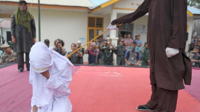 FILE PHOTO: An Acehnese woman gets caned by a religious officer, for spending time in close proximity with a man who is not her husband, which is against Sharia law, in Banda Aceh on February 27, 2017. Aceh is the only province in the world’s most populous Muslim-majority country that imposes sharia law. People can face floggings for a range of offences — from gambling, to drinking alcohol, to gay sex. / AFP PHOTO / CHAIDEER MAHYUDDIN