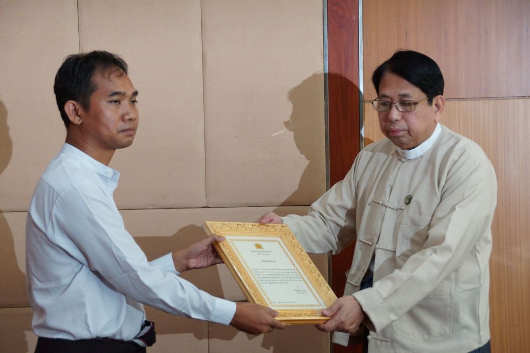 Swe Win receiving an award from Information Minister Pe Myint in 2016. Photo: MOI