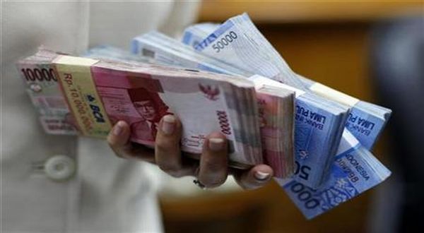 An employee holds Indonesian rupiah banknotes at a money changer in Jakarta January 27, 2010.  REUTERS/Beawiharta