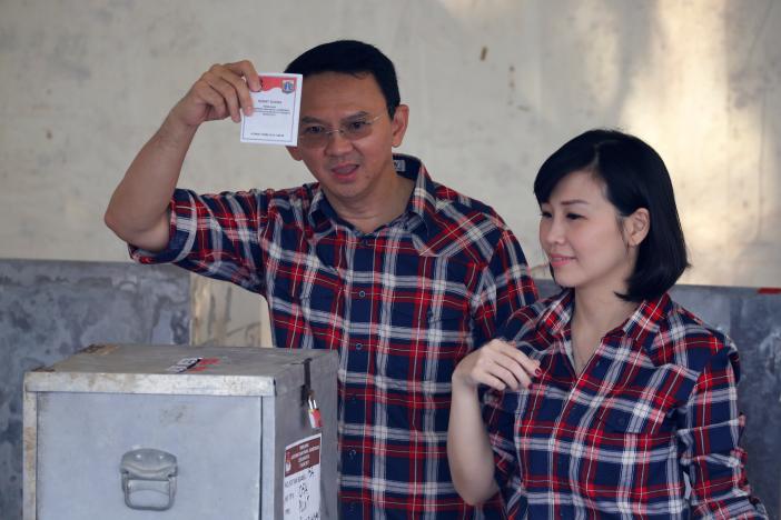 Former Jakarta Governor Basuki Tjahaja Purnama (L) shows his ballot as he stands beside his wife Veronica Tan during the Jakarta gubernatorial election on February 15, 2017. REUTERS/Beawiharta