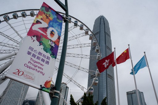 A poster commemorating the 20th anniversary of Hong Kong’s handover from Britain to China is displayed near the hoisted flags of Hong Kong and China. Photo: Anthony Wallace / AFP