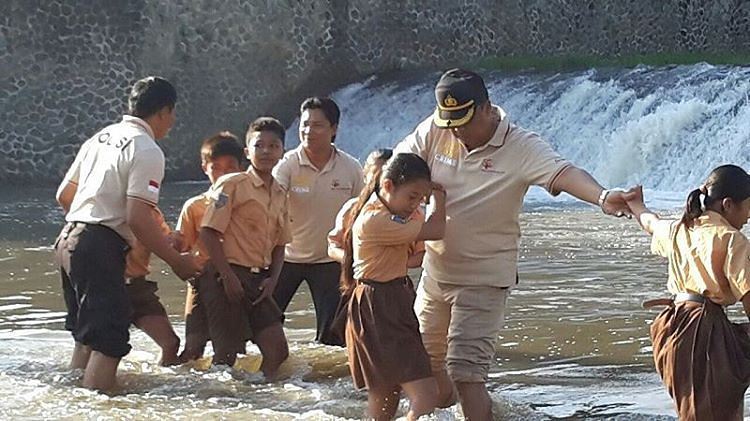 Students in North Bali are helped by police across a river on their way to school. Photo: Facebook