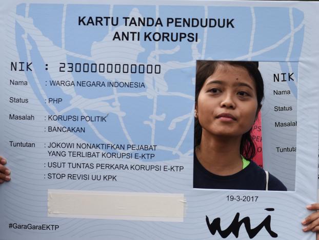 An activist hold a placard in the shape of national identity cards (KTP) during a protest calling for the investigation into alleged corruption linked to the procurement of the electronic cards by government officials in Jakarta, Indonesia March 19, 2017 in this photo taken by Antara Foto.  Antara Fot/Hafiz Mubarak/via REUTERS