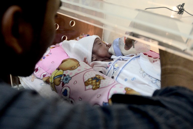 This photo taken on March 17, 2017 shows Prayogi feeding his daughter Maryamah Sudigyo, who was born prematurely, as she rests in an incubator in their home in Bogor.  
Maryamah is one of hundreds of premature babies born in Indonesia benefiting from the pioneering work of an engineering professor who is building incubators and lending them for free to low-income families in a bid to fill a gap in the healthcare system. Indonesia has the fifth greatest number of premature births of any nation in the world, at 675,700 a year, according to the World Health Organization. AFP PHOTO / GOH Chai Hin 
