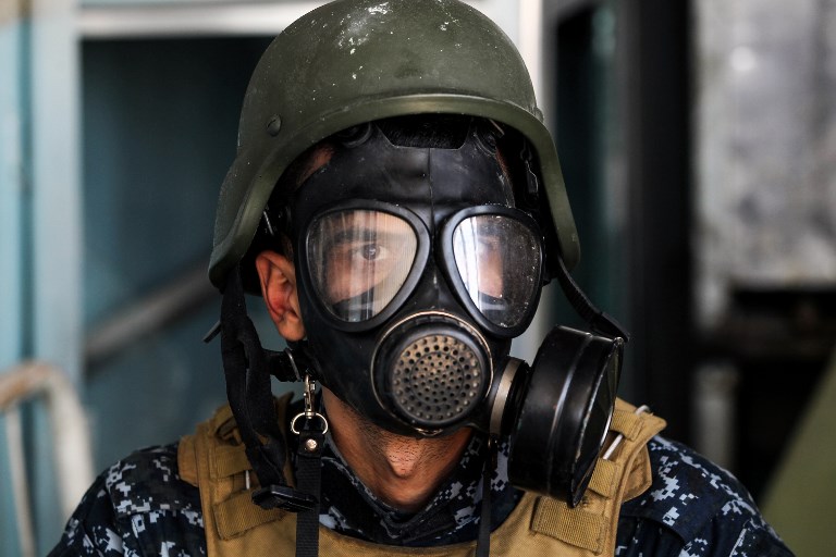 A member of the Iraqi forces wears a gas mask in the old city of Mosul on April 16, 2017. Gas masks and ballistic vests are frequently used by reporters around the world. Photo: AFP