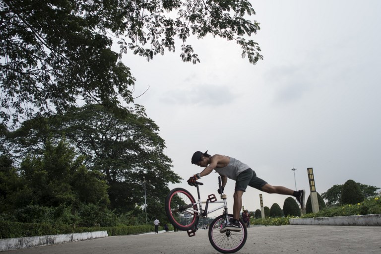 This photo taken on April 30, 2017 shows Htet Wai Yan Oo, 23, performing a stunt in park in Yangon. 
Skidding and screeching across the concrete the young bikers perform a carefully choreographed dance of gravity-defying stunts, a dazzling display of Myanmar’s thriving youth culture on the streets of its biggest city. / AFP PHOTO / YE AUNG THU / TO GO WITH: Myanmar-lifestyle-cycling