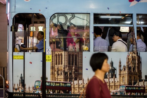 In this picture taken on May 24, 2017, a tram is seen decorated with Britain’s Houses of Parliament as commuters travel during the evening in Hong Kong.
From its rattling trams and racecourses to its legal system and the ubiquitous consumption of Spam, Britain’s colonial legacy still resonates through Hong Kong. But almost 20 years since the city was handed back to China under a deal that made it semi-autonomous, colonial emblems have become a symbol of protest.  / AFP PHOTO / Anthony WALLACE / TO GO WITH Hong Kong-China-Britain-politics-history-culture-handover, FEATURE by Laura MANNERING