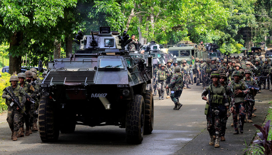 An armored personnel carrier and government troops march on Thursday to begin their assault against insurgents from the so-called Maute group, who have taken over large parts of Marawi City. PHOTO: Romeo Ranoco/Reuters