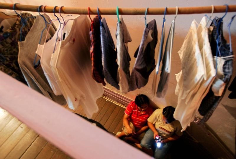 Abused foreign domestic helpers use mobile phones at a corridor of Bethune House, which provides temporary shelter for abused victims, in Hong Kong October 23, 2006.     Photo: Paul Yeung/Reuters