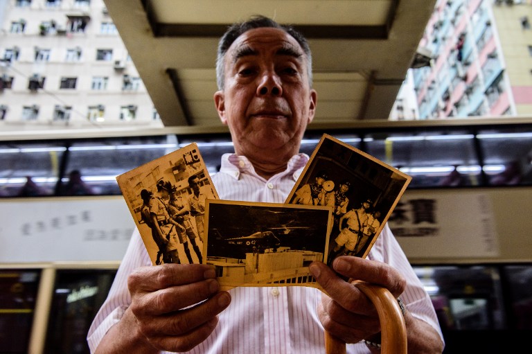 Former police inspector James Elms, 75, stands near the old Metropole Hotel building on April 21st 2017, as he holds a photo (C) showing the hotel roof on which he landed upon in a helicopter while deployed during a mission to deal with rioters in May 1967 and two other photos of Elms while he was on duty during the riots in Hong Kong. Photo: Anthony Wallace/AFP