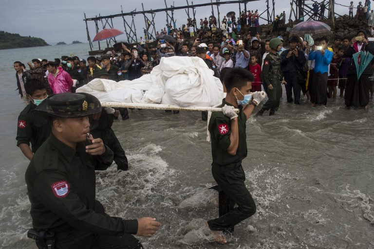 Myanmar military members carry a dead body at Sanhlan village on June 8, 2017. / AFP PHOTO / Ye Aung Thu