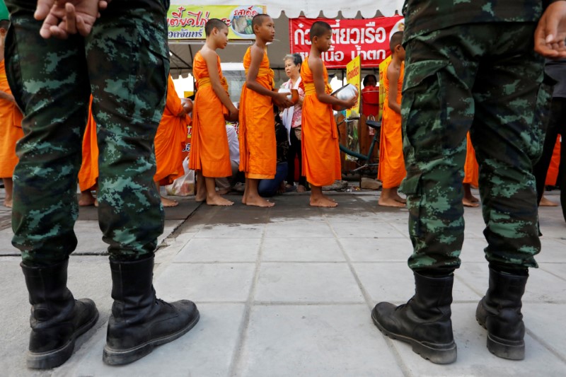 Buddhist monks receive food from people while soldiers watch on outside Dhammakaya temple in Pathum Thani province, Thailand, February 23, 2017. File Photo: Jorge Silva/ Reuters