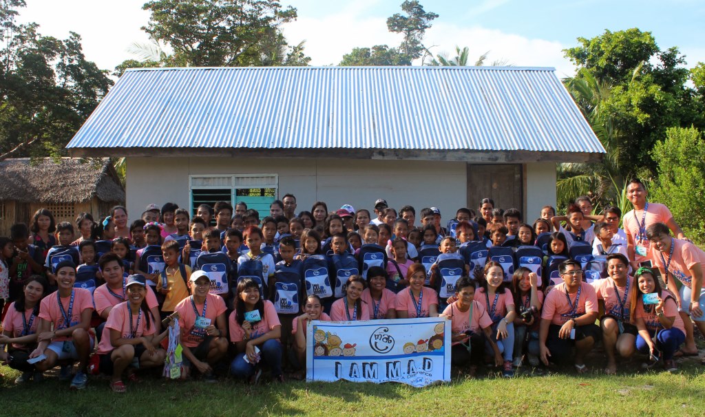 Millenial volunteers together with the beneficiaries and their parents pose for a souvenir photo. Firing up the spirit of volunteerism while traveling. I am M.A.D. (Making A Difference) conquered the town of Magdiwang, Sibuyan Island, Romblon for its 32nd MAD Camp area at Tomas and Maria Maglaya Memorial School.