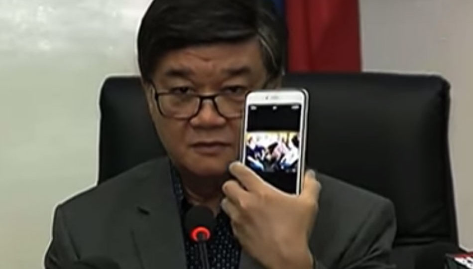 Justice Secretary Vitaliano Aguirre II shows the media his purported proof that opposition figures met in Marawi City days before clashes between government troops and terror groups began. The photo turned out to be a 2015 image taken at the Iloilo airport. PHOTO: Screengrab from TV Patrol