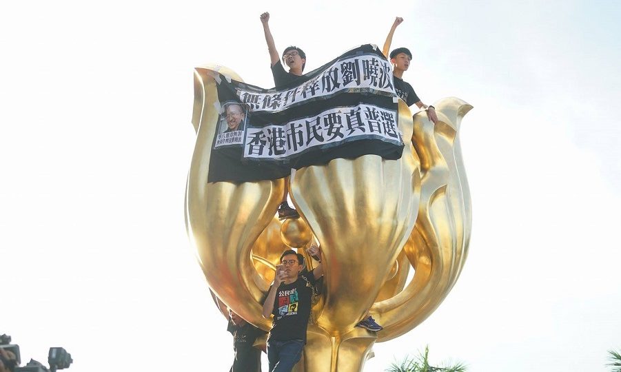 Photo: Activists clambered onto the statue, which was gifted to Hong Kong by China upon its return in 1997, with a banner reading “Hong Kong people need genuine universal suffrage”. Photo: League of Social Democrats via Facebook