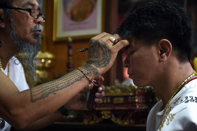This photograph taken on May 20, 2017 shows Hermit Toon inscribing a protective charm with holy oil on the forehead of a Taiwanese client. Photo: Lillian Suwanrumpha/ AFP