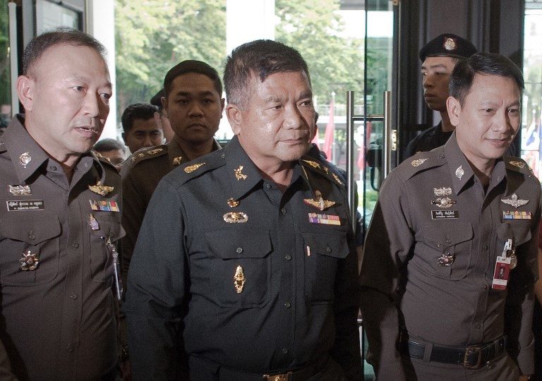 Thai Army Lieutenant General Manas Kongpan (C) being surrounded by police officers as he turns himself in at the police headquarters in Bangkok. Photo: AFP / Nicolas Asfouri