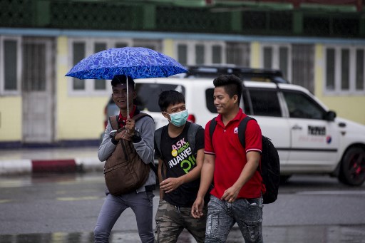 A man wears a face mask while walking with friends in Yangon. Photo: AFP / Aung Kyaw Htet