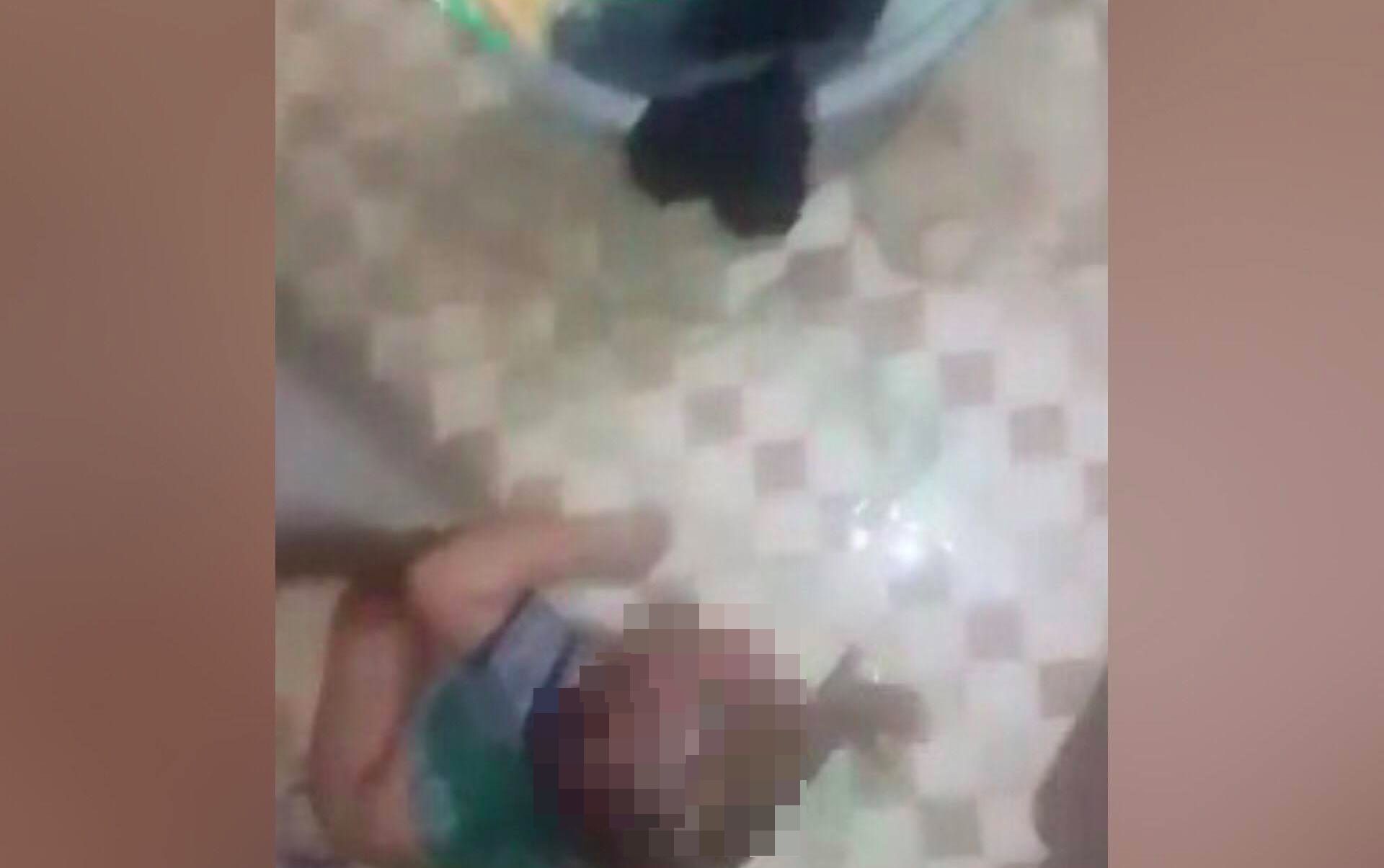 A still from a distressing video posted to Facebook, showing a mother dousing her baby with dish soap. 