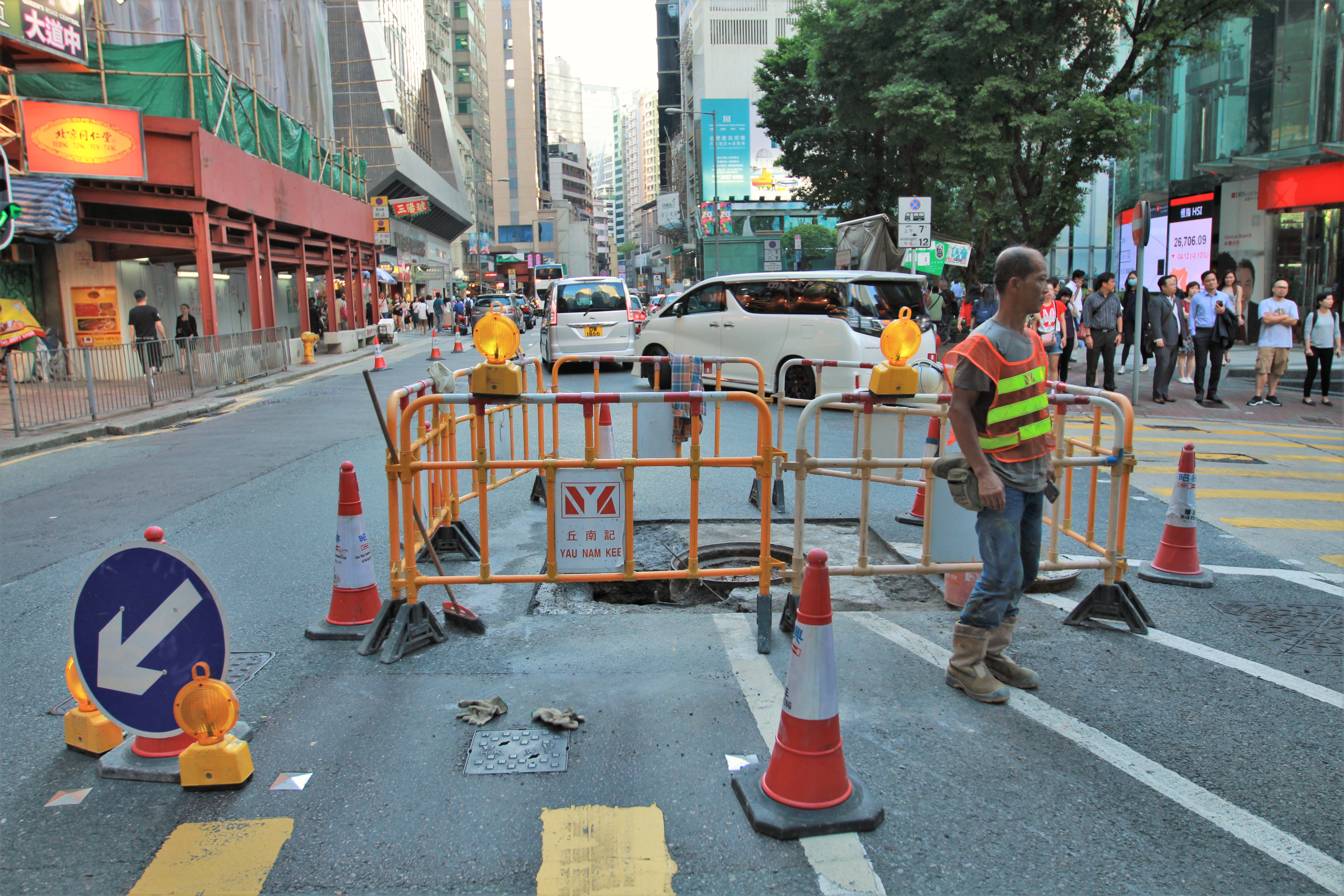 A construction worker stands by the hole on Queen’s Road Central, one of the busiest thoroughfares in Hong Kong. Photo: Cecilia Wong/Coconuts Media