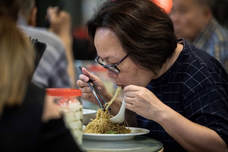 This picture taken on July 25, 2017 shows a woman eating noodles, handmade using a traditional bamboo pole technique, at a restaurant in Hong Kong.
From decades-old holes in the wall to multi-million dollar businesses, Hong Kong’s noodle scene is a sprawling moneyspinner in a city that runs on quick and affordable comfort food. / AFP PHOTO / Dale DE LA REY / TO GO WITH HongKong-lifestyle-food-noodles-business, FEATURE by Elaine YU