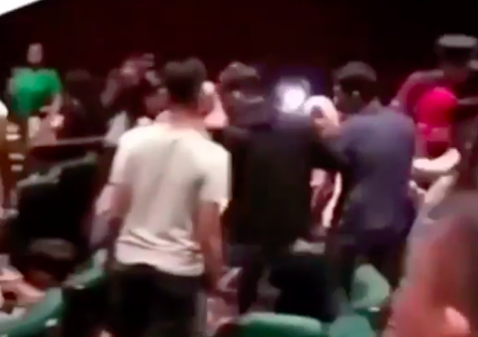 Cinema goers carrying out the supposedly possessed woman out of the cinema. Photo: Video screengrab
