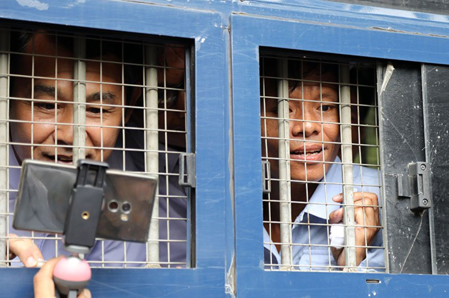Journalists Aye Nai (L) and Lawi Weng speak to journalists from inside a prisoner transport vehicle outside the courthouse in Hsipaw in Shan State on July 28, 2017. Photo: AFP