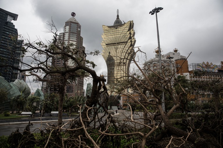 A man (lower C) is pictured through trees damaged from Tyhoon Hato on August 23 as he takes a picture in front of the Grand Lisboa hotel as severe tropical storm Pakhar passes over Macau on August 27, 2017. AFP PHOTO / DALE DE LA REY