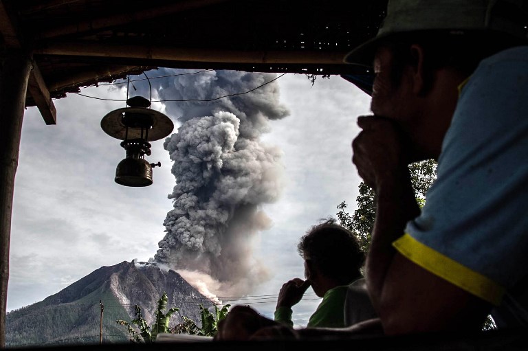 Villagers look on as Mount Sinabung volcano spews thick volcanic ash, as seen from Beganding village in Karo, North Sumatra province, on May 19, 2017. Sinabung roared back to life in 2010 for the first time in 400 years. After another period of inactivity, it erupted once more in 2013 and has remained highly active since. Photo: Ivan Damanik/AFP