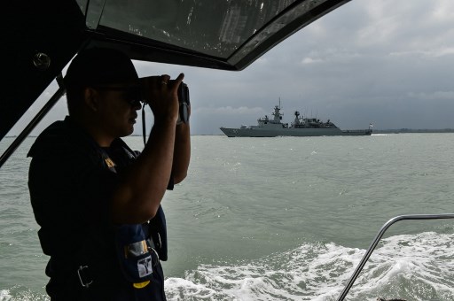 A member of the Malaysian Maritime Enforcement Agency officer uses a pair of binoculars to scan the sea. PHOTO: AFP / MOHD RASFAN