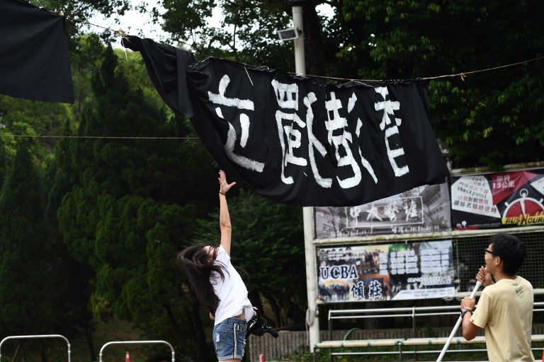 In this photo taken on September 20, 2017, a woman tries to untangle a banner calling for semi-autonomous Hong Kong to split from the mainland, at the Chinese University of Hong Kong (CUHK) campus in Hong Kong.
Universities have become the latest battleground over freedoms in Hong Kong as a ban on signs on campuses advocating independence from China sparked fresh fears that the city’s liberties are under threat.   / AFP PHOTO / Anthony WALLACE