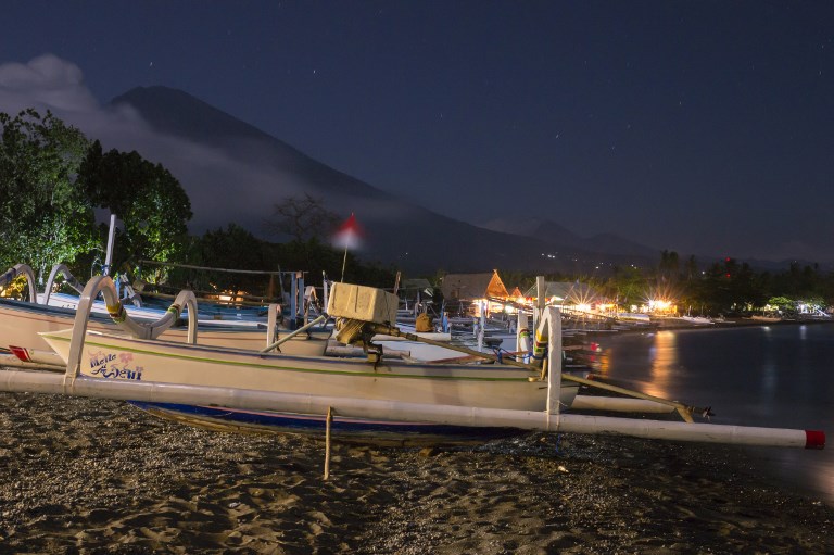 Fishing boats are seen at night in the foreground as Mount Agung volcano looms in the background at Amed beach in Karangasem, Indonesia’s resort island of Bali, on September 30, 2017. Photo: Bay Ismoyo/AFP