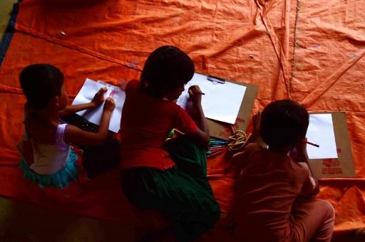 In this photograph taken on September 11, 2017, Rohingya Muslim refugee children draw pictures at a safe house in Kutupalong refugee camp in the Bangladeshi town of Teknaf. The lost Rohingya boy made the journey from Myanmar alone, following strangers from other villages across rivers and jungle until they reached Bangladesh, where he had no family and no idea where to go. MUNIR UZ ZAMAN / AFP
