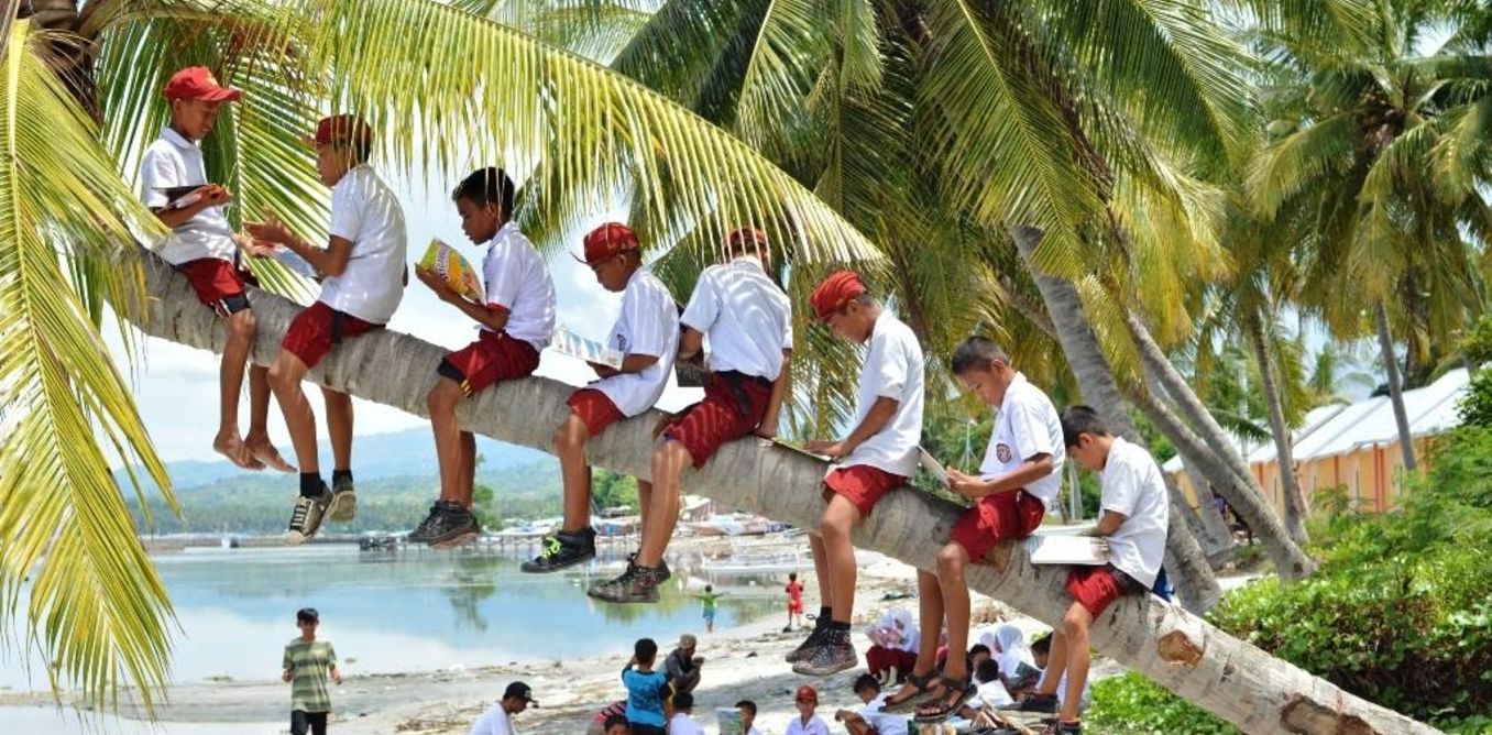 School children read books at Palipis beach in Mandar, West Sulawesi. The books were brought by library boat. Pattingalloang, which was part of a network of moving libraries called Pustaka Bergerak. Photo: Urwa/Pustaka Bergerak, CC BY-NC-SA