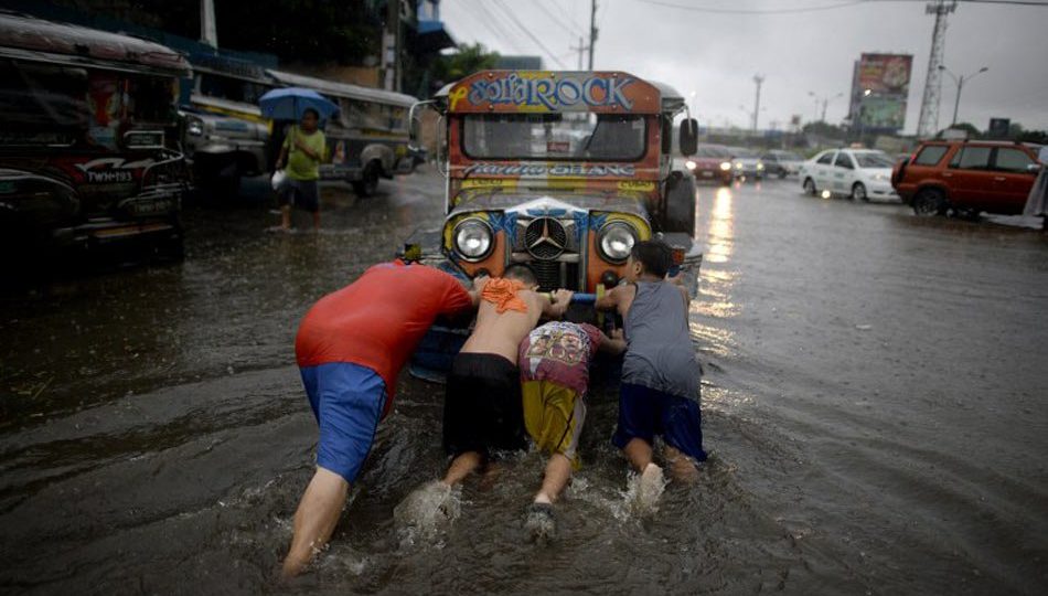 People push a jeepney out of a flooded street in Manila on August 13, 2016. Floods inundated major thoroughfares in the capital after days of monsoon rains. PHOTO: Noel Celis/AFP
