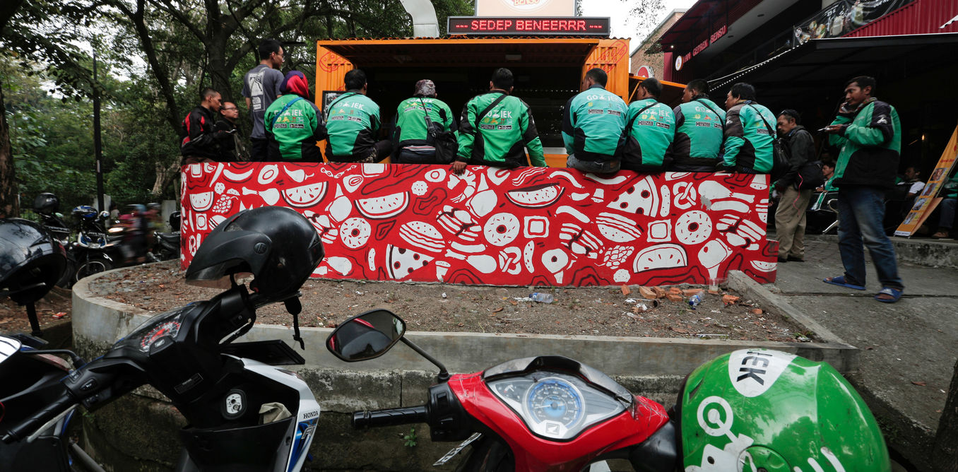 Go-Jek drivers sit as they wait for their orders at a food stall in Jakarta. File photo by REUTERS/Beawiharta