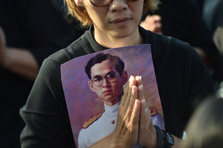 A mourner holds an image of the late Thai King Bhumibol Adulyadej as she waits for his funeral procession to take place in Bangkok on October 26, 2017.
AFP PHOTO / Ye Aung Thu