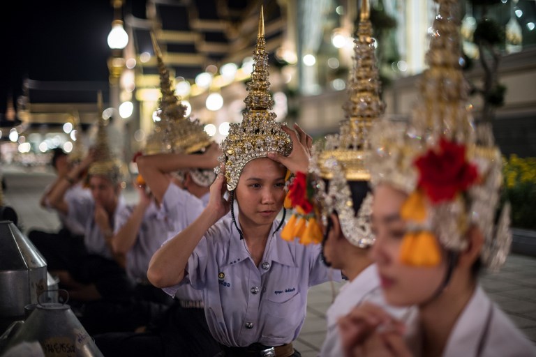 In this photo taken on October 21, 2017 female dancers adjust their traditional Thai ceremonial head gear before walking into the main courtyard for a rehearsal presentation at the pavilion where Thailand’s late king Bhumibol Adulyadej will be cremated on October 26. AFP PHOTO / Roberto Schmidt