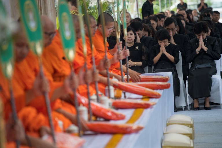 People clad in black in a sign of mourning pray as they listen to Buddhist monks chant mantras during a ceremony led by monks in front of Bangkok’s City Hall on October 13, 2017, marking one year since the death of King Bhumibol Adulyadej. 
AFP PHOTO / Roberto Schmidt