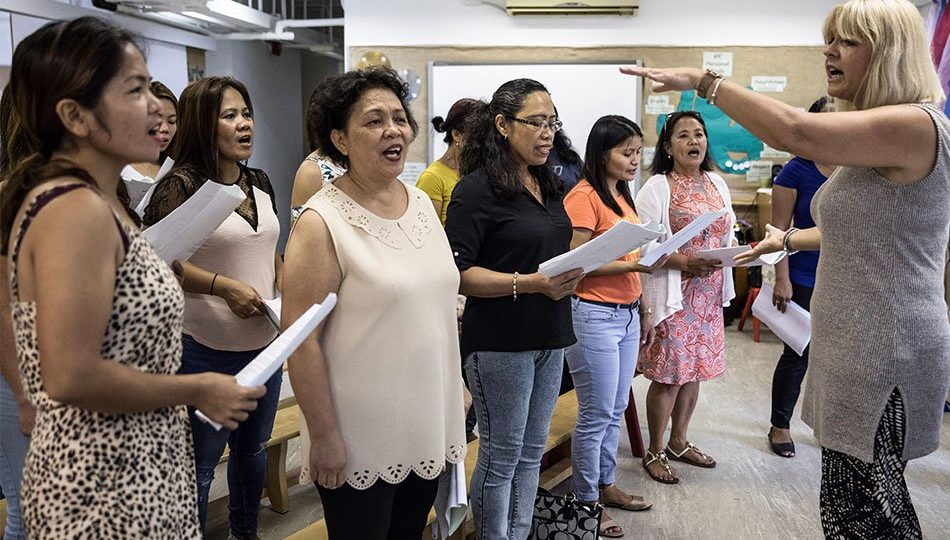 In this picture taken on September 3, 2017, “Unsung Heroes” choir founder Jane Englemann (R) leads her group of Filipina domestic workers during a practice session inside a kindergarten school’s classroom in Hong Kong. PHOTO: Dale De La Rey, AFP