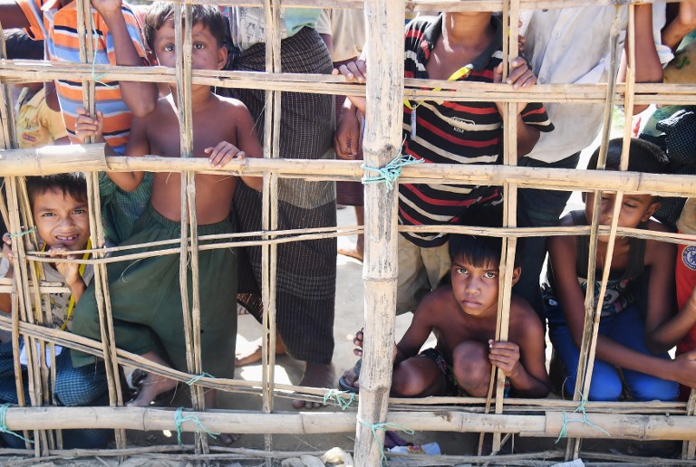 Young Rohingya Muslim refugees look on through a temporary bamboo barricade at the Thankhali refugee camp in Bangladesh’s Ukhia district on November 10, 2017. / AFP PHOTO / Dibyangshu SARKAR