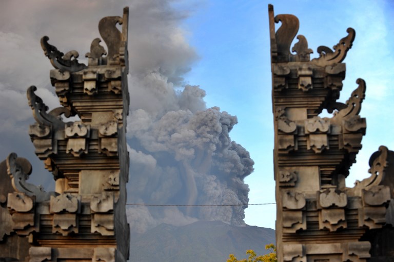 Mount Agung’s eruption is seen between Balinese temple at Kubu sub-district in Karangasem Regency on Indonesia’s resort island of Bali on November 26, 2017. 
Mount Agung belched smoke as high as 1,500 metres above its summit, sparking an exodus from settlements near the mountain. Photo: Sonny Tumbelaka/AFP