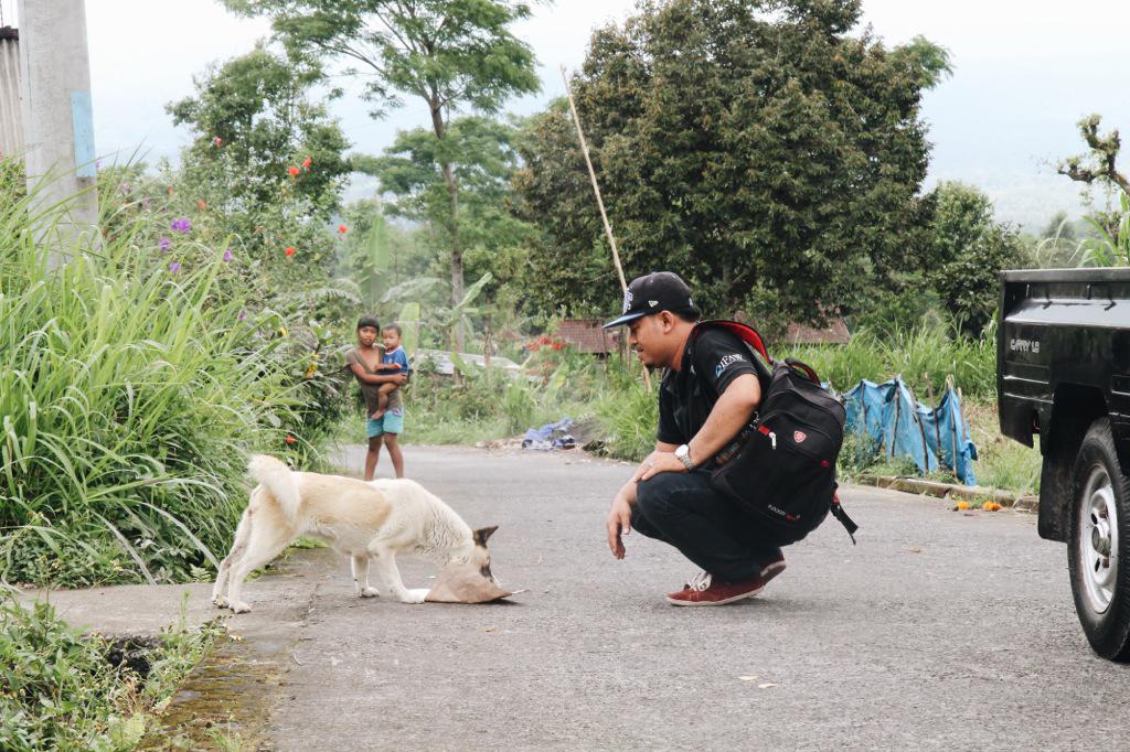 A BAWA staff member feeds a dog on the slopes of Mt. Agung. Photo: Julianne Greco/Coconuts Bali