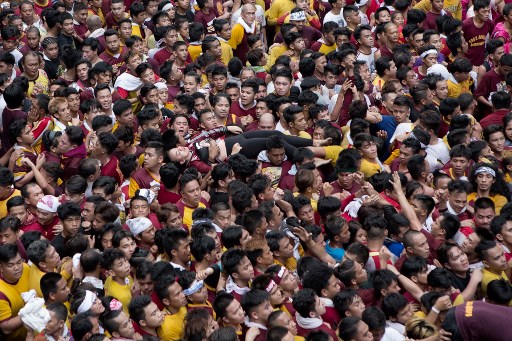 A devotee who collapsed is carried by the crowd as they try to reach the carriage of Black Nazarene during the annual religious procession in Manila on January 9, 2018. 
A sea of heaving, towel-waving humanity swarmed a black statue of a cross-bearing Jesus Christ in the Philippine capital on January 9 as the Catholic faithful joined one of the nation’s largest religious festivals. / AFP PHOTO / jake c salvador