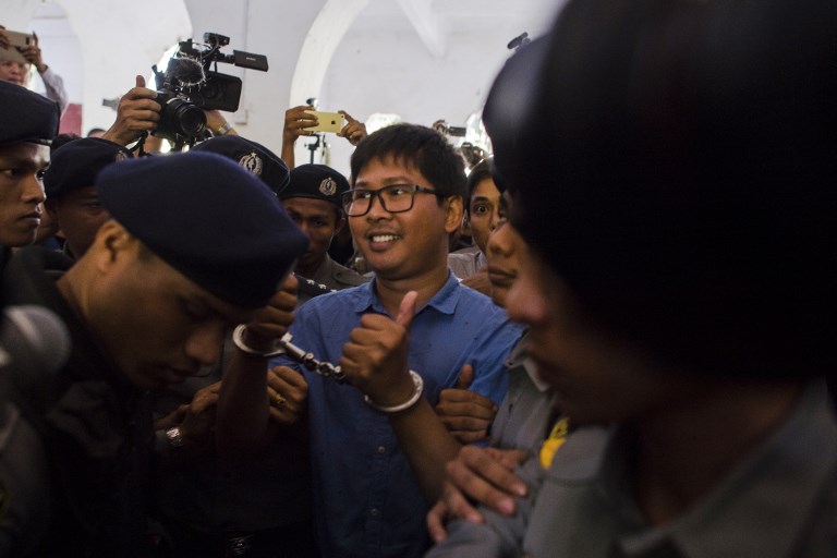 Reuters journalist Wa Lone (C) is escorted by police as he arrives for a court appearance in Yangon on January 10, 2018. / AFP PHOTO / YE AUNG THU