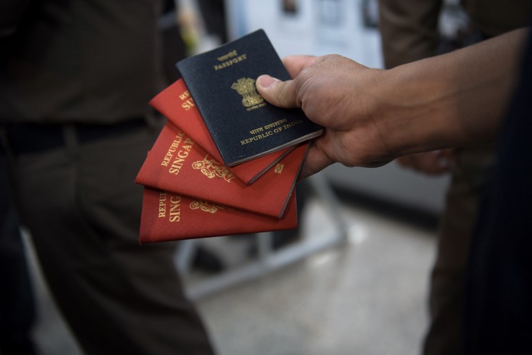 An Thai immigration officer displays fake passports in his hand as he speaks to journalists during a press conference in Bangkok, Jan. 19, 2018. Photo: Roberto Schmidt/ AFP